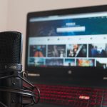 Close-up of a microphone and laptop on a desk suitable for home recording or podcasting.