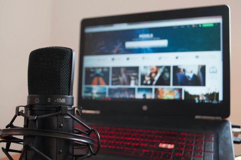 Close-up of a microphone and laptop on a desk suitable for home recording or podcasting.