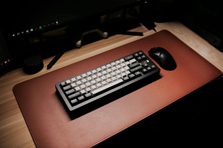 Stylish computer desk featuring a sleek mechanical keyboard and mouse on a brown mat.