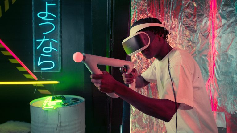 An adult enjoys virtual reality gaming with neon lighting and modern equipment.