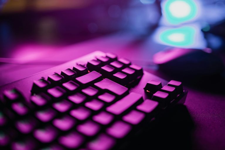 A close-up view of an RGB backlit gaming keyboard with a vibrant purple glow, perfect for tech and gaming enthusiasts.